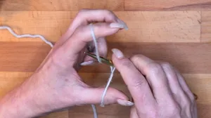 Ziehe den Zeigefingerfaden durch die so entstandene Schlaufe und ziehe die Schlinge mit dem Daumen zu.. Maschen Anschlagen