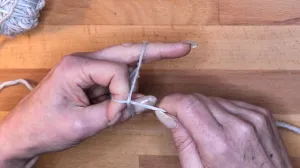 Hole durch die so entstandene Schlaufe den Arbeitsfaden vom Knäuel.. Maschen Anschlagen