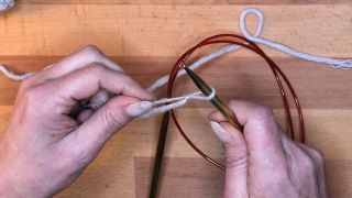 Lege die Schlaufe auf deine Nadel und ziehe mit dem Arbeitsfaden die Schlaufe zu maschen anschlagen