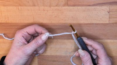 Mache einen Laufknoten ohne langen Faden und lege diese Schlaufe auf deine Häkelnadel. maschen anschlagen