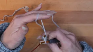 Führe den Arbeitsfaden zwischen Strick- und Häkelnadel nach hinten durch, sodass der Faden wieder hinter der Stricknadel liegt.. Maschen Anschlagen