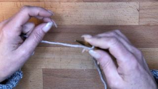 Starte mit einem Laufknoten auf der Nadel in der rechten Hand und halte den Arbeitsfaden mit Ringfinger und kleinem Finger der rechten Hand fest. maschen anschlagen