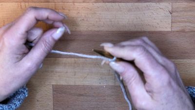 Starte mit einem Laufknoten auf der Nadel in der rechten Hand und halte den Arbeitsfaden mit Ringfinger und kleinem Finger der rechten Hand fest. maschen anschlagen