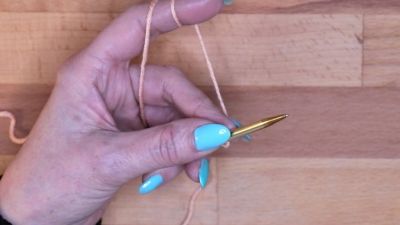 Mache einen Laufknoten und setze ihn auf deine linke Nadel. maschen anschlagen