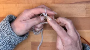 Lass die Schlaufe vom Daumen gleiten und ziehe den Faden um die so entstandene Masche auf der Nadel fest.. Maschen Anschlagen