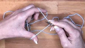 Drehe dann die Spitze der Nadel zu dir her, sodass eine Schlaufe um die Nadel liegt. Der Faden vom Zeigefinger liegt über dem Daumenfaden. . Maschen Anschlagen