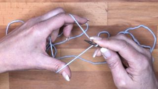 Drehe dann die Spitze der Nadel zu dir her, sodass eine Schlaufe um die Nadel liegt. Der Faden vom Zeigefinger liegt über dem Daumenfaden.  maschen anschlagen