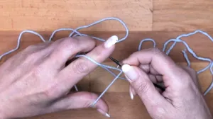 Führe die Nadel über den Faden vom Zeigefinger. Maschen Anschlagen